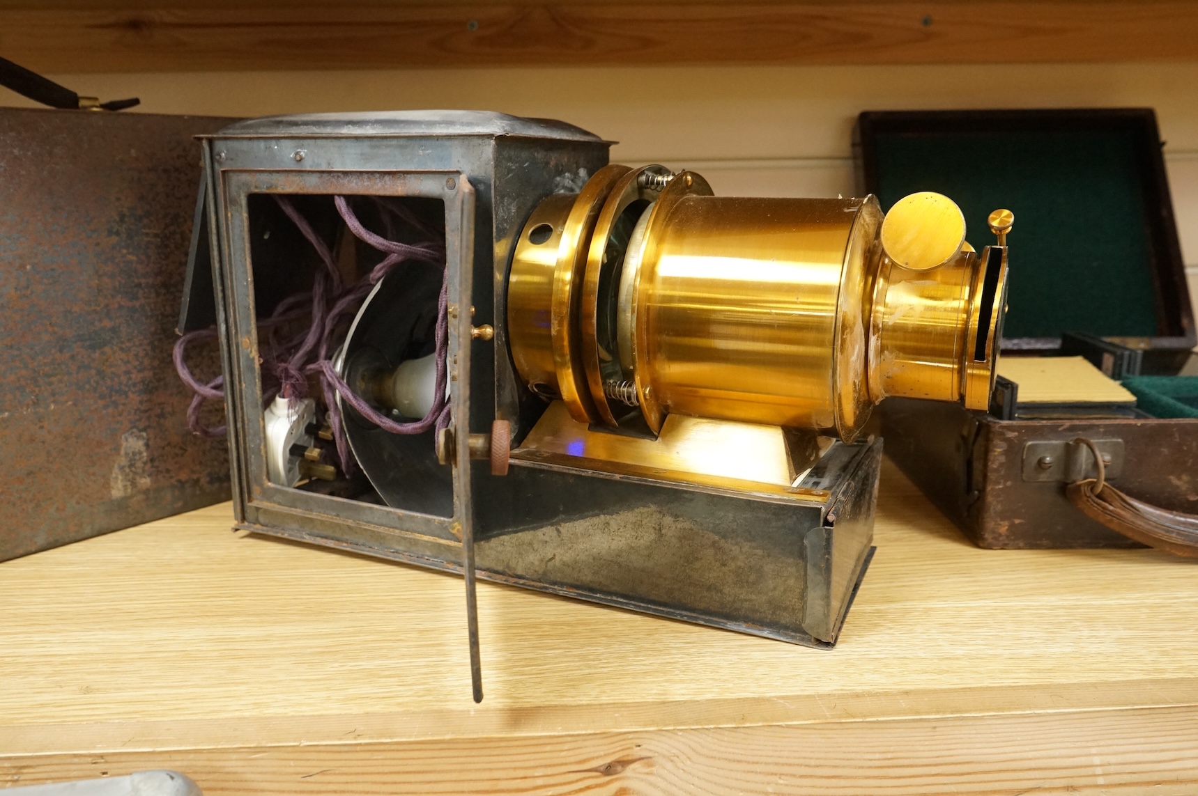 A tinplate and brass magic lantern, converted to an electric lamp and missing the original chimney, in a tin case, together with a case of slides, mostly biblical related.